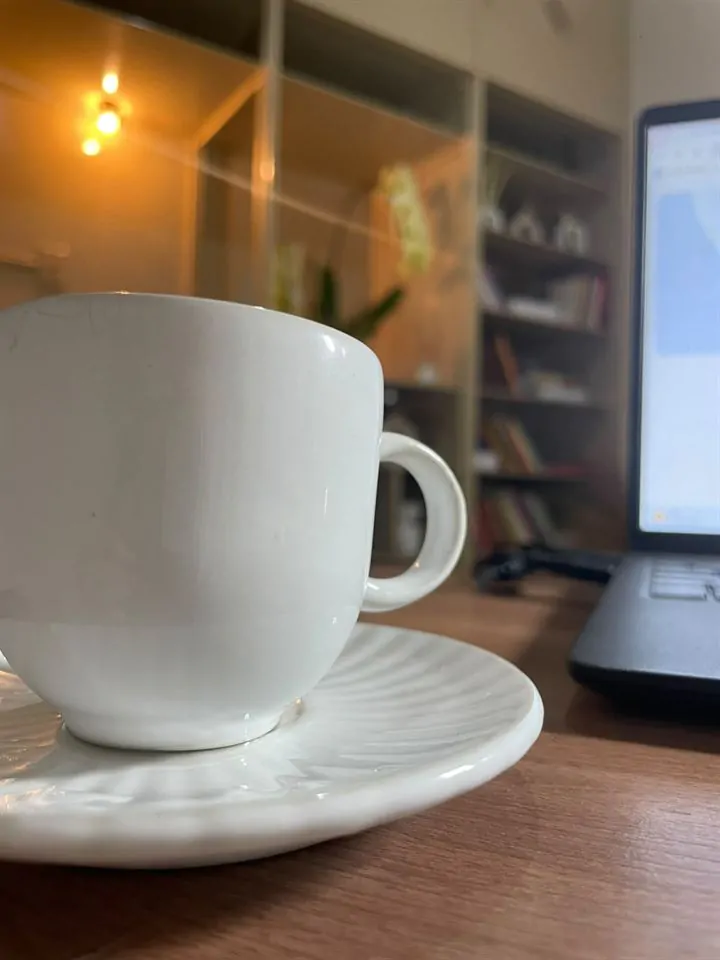 Xícara de café com estante de livros ao fundo