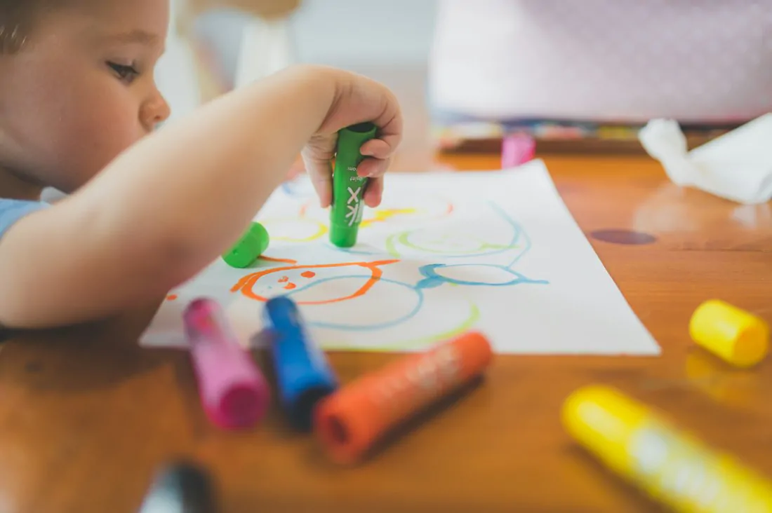 Criança desenhando com canetinhas